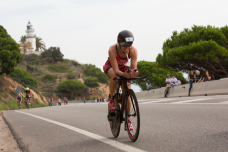 Ciclista participant a un triatló amb el far de Calella de fons